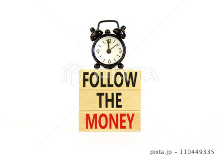 Follow the money symbol. Concept words Follow the money on beautiful wooden blocks. Beautiful white table white background. Black alarm clock. Business and follow the money concept. Copy space. 110449335