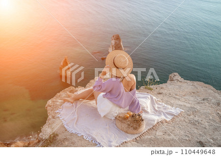 woman sea travel. photo of a beautiful woman with long blond hair in a pink shirt and denim shorts and a hat having a picnic on a hill overlooking the sea woman sea travel. photo of a beautiful woman with long blond hair in a pink shirt and denim shorts and a hat having a picnic on a hill overlooking the sea 110449648