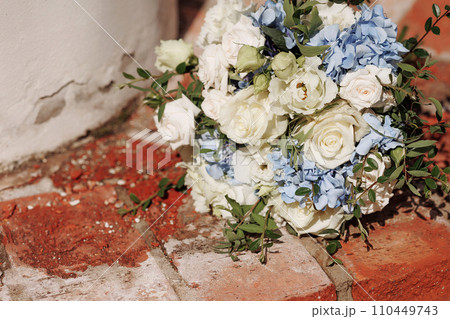 Festive wedding bouquet tied with a ribbon on a brick background. Festive wedding bouquet tied with a ribbon on a brick background. 110449743