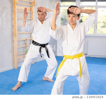 Teen boy and middle-aged man wearing kimono training karate techniques Teen boy and middle-aged man wearing kimono training karate techniques 110451024