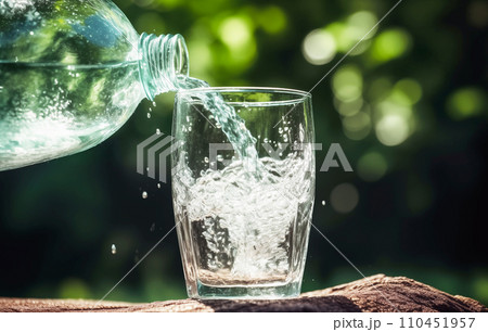 Drink water pouring in to glass mug from water plastic bottle on green background.  110451957