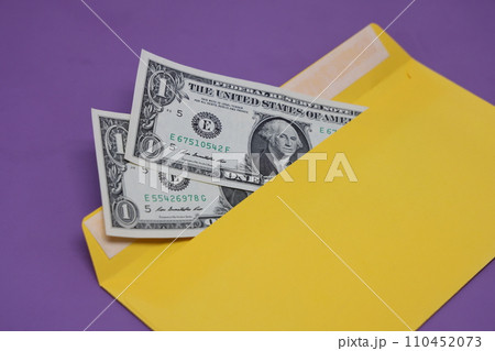 Banknotes in a yellow envelope on a purple background. Bribery concept. Salary in envelopes. Financial fraud. Banknotes in a yellow envelope on a purple background. Bribery concept. Salary in envelopes. Financial fraud. 110452073