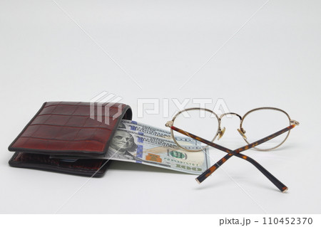 Brown wallet with banknotes and glasses. Brown frame. Symbol of accounting and family finance planning. Brown wallet with banknotes and glasses. Brown frame. Symbol of accounting and family finance planning. 110452370