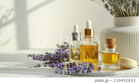 Beauty product display, slender flacons and oils, arranged with fresh lavender, on a monochrome ivory surface Beauty product display, slender flacons and oils, arranged with fresh lavender, on a monochrome ivory surface 110452633