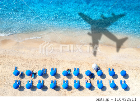 Aerial view of blue sea, airplane shadow, sandy beach, umbrellas 110452811