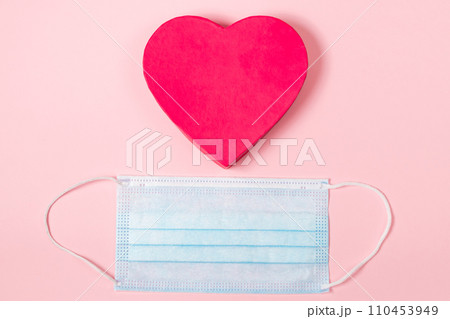 Valentine's day concept during the coronavirus pandemic. Pink heart and medical mask. Place for text. 110453949