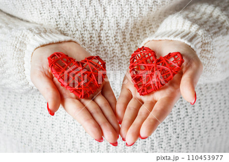 Woman holds red hearts in her hands. Symbol of Valentine's Day and lovers. Woman holds red hearts in her hands. Symbol of Valentine's Day and lovers. 110453977
