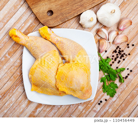 Raw chicken legs and condiments on wooden table Raw chicken legs and condiments on wooden table 110456449