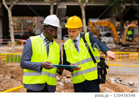 Foreman and engineer check correctness of the pipeline repair on street Foreman and engineer check correctness of the pipeline repair on street 110456546
