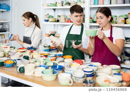 Young man and young woman examining pottery 110456908