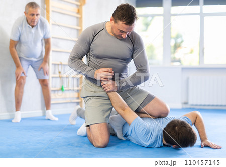 Two athlete men of different age in sportswear practicing self-defense sparring in hall 110457145