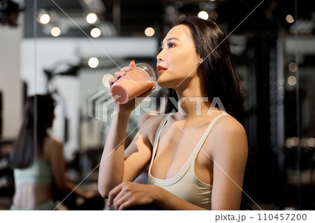 ジムでプロテインを飲む女性トレーニー	 110457200