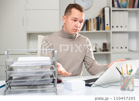 Portrait of upset office worker sitting at table Portrait of upset office worker sitting at table 110457205
