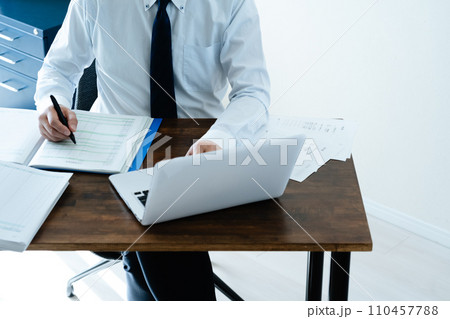 帳簿を確認する男性ビジネスマンの手元 110457788