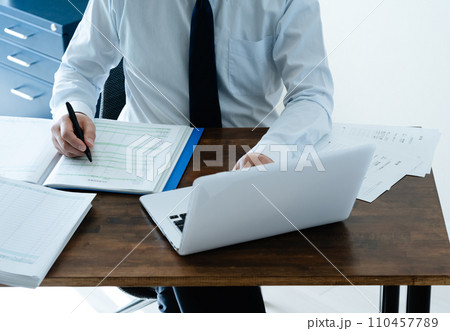 帳簿を確認する男性ビジネスマンの手元 帳簿を確認する男性ビジネスマンの手元 110457789