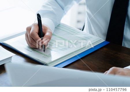 帳簿を確認する男性ビジネスマンの手元 帳簿を確認する男性ビジネスマンの手元 110457796