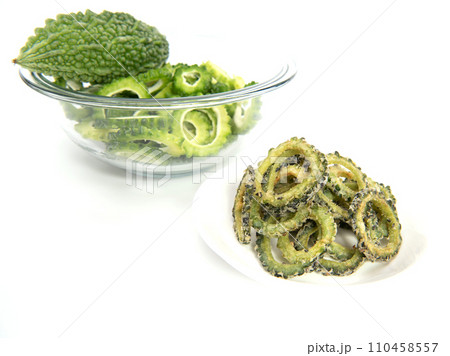 Homemade bitter gourd chips in glass bowl isolated on white background. Homemade bitter gourd chips in glass bowl isolated on white background. 110458557