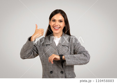 Joyful woman giving thumbs up with smartwatch 110458883