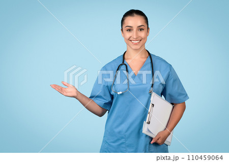 Smiling female nurse in scrubs with clipboard presenting free space 110459064