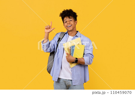 Cheerful student gesturing size with hand on yellow background 110459070