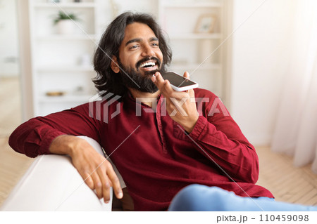 Positive indian guy recording voice mail on smartphone Positive indian guy recording voice mail on smartphone 110459098