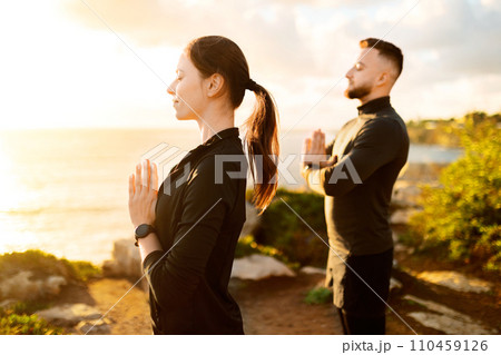 Serene man and woman practicing outdoor meditation at sunset 110459126