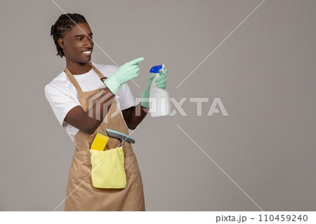 Cleaning Advertisement. Young Black Male Cleaner Holding Detergent Spray And Pointing Aside Cleaning Advertisement. Young Black Male Cleaner Holding Detergent Spray And Pointing Aside 110459240