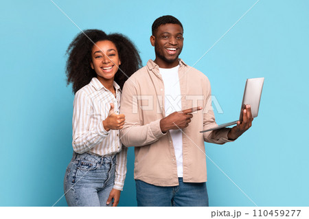 Excited black couple with laptop showing thumbs up on blue Excited black couple with laptop showing thumbs up on blue 110459277