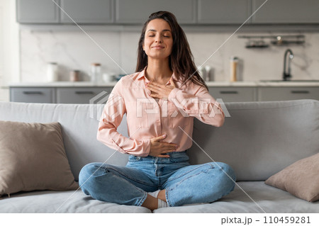 Relaxed young woman meditating on sofa at home Relaxed young woman meditating on sofa at home 110459281