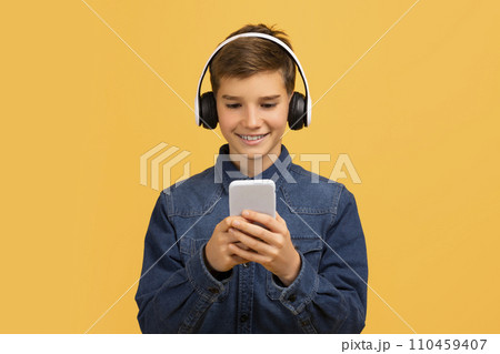 Smiling Teen Boy Wearing Wireless Headphones Using Modern Smartphone, 110459407