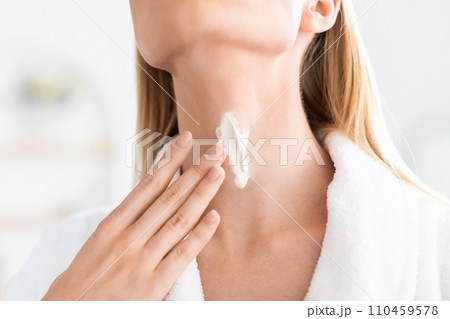 Cropped shot of blonde lady applying moisturizer on neck skin 110459578