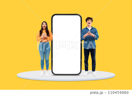 Excited teens with smartphones by huge blank display 110459860