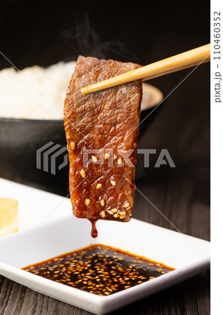 焼肉をタレをつけて食べる 焼肉をタレをつけて食べる 110460352