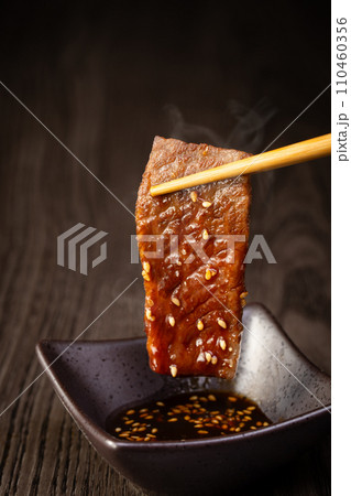 焼肉をタレをつけて食べる 110460356
