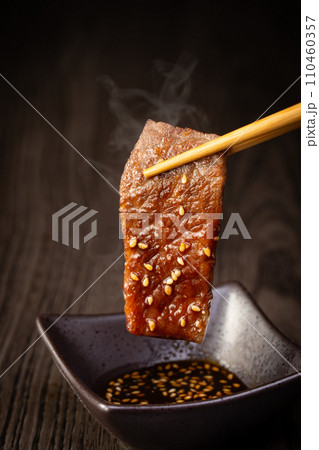 焼肉をタレをつけて食べる 110460357