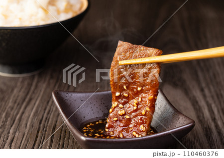 焼肉をタレをつけて食べる 110460376