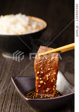 焼肉をタレをつけて食べる 110460380