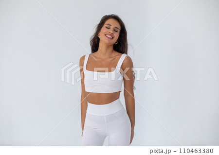 Beautiful brunette girl in a white top and tights posing on white background 110463380