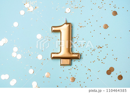 Gold candle in the form of number one. 110464385