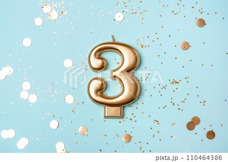 Gold candle in the form of number three. 110464386