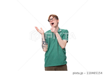 young caucasian male student with red hair and tattoo stands thoughtfully and is bored 110465154