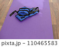 Fabric blue leg weights lie on a yoga mat. Sport equipment. Purple yoga mat. 110465583