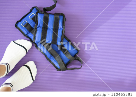 Female feet in white socks stand on a yoga mat where fabric weights for the feet lie. Female feet in white socks stand on a yoga mat where fabric weights for the feet lie. 110465593