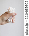 Cotton swabs are held in the hand. A woman's hand holds a lot of cotton swabs in her hand on a white background. 110465602