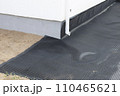 Laying a black waterproofing membrane around the foundation of a house. Construction of the blind area of the house. Reliable protection of the foundation from moisture. White pipe for draining 110465621