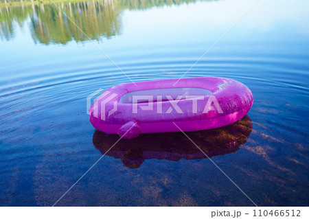 A pink children's swimming circle on the water of a calm lake. 110466512