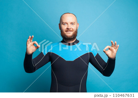 Portrait of scuba diver in diving mask showing okay sign on blue studio wall background Portrait of scuba diver in diving mask showing okay sign on blue studio wall background 110467631