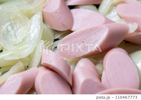 魚肉ソーセージと玉ねぎをフライパンで炒める調理シーン。 110467773