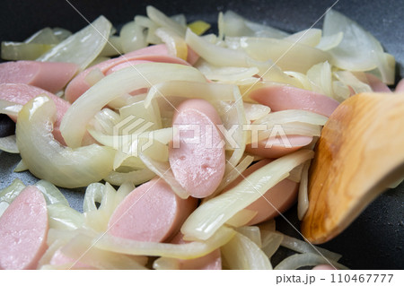 魚肉ソーセージと玉ねぎをフライパンで炒める調理シーン。 110467777