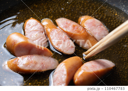 卵とじするためにウインナーをだし汁で煮る調理シーン。 110467783